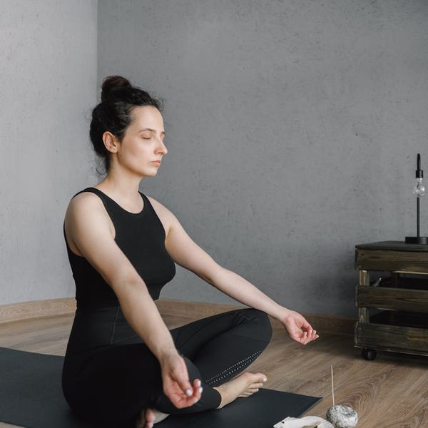 Smiling woman sitting in a lotus yoga pose, feeling serene and energized.